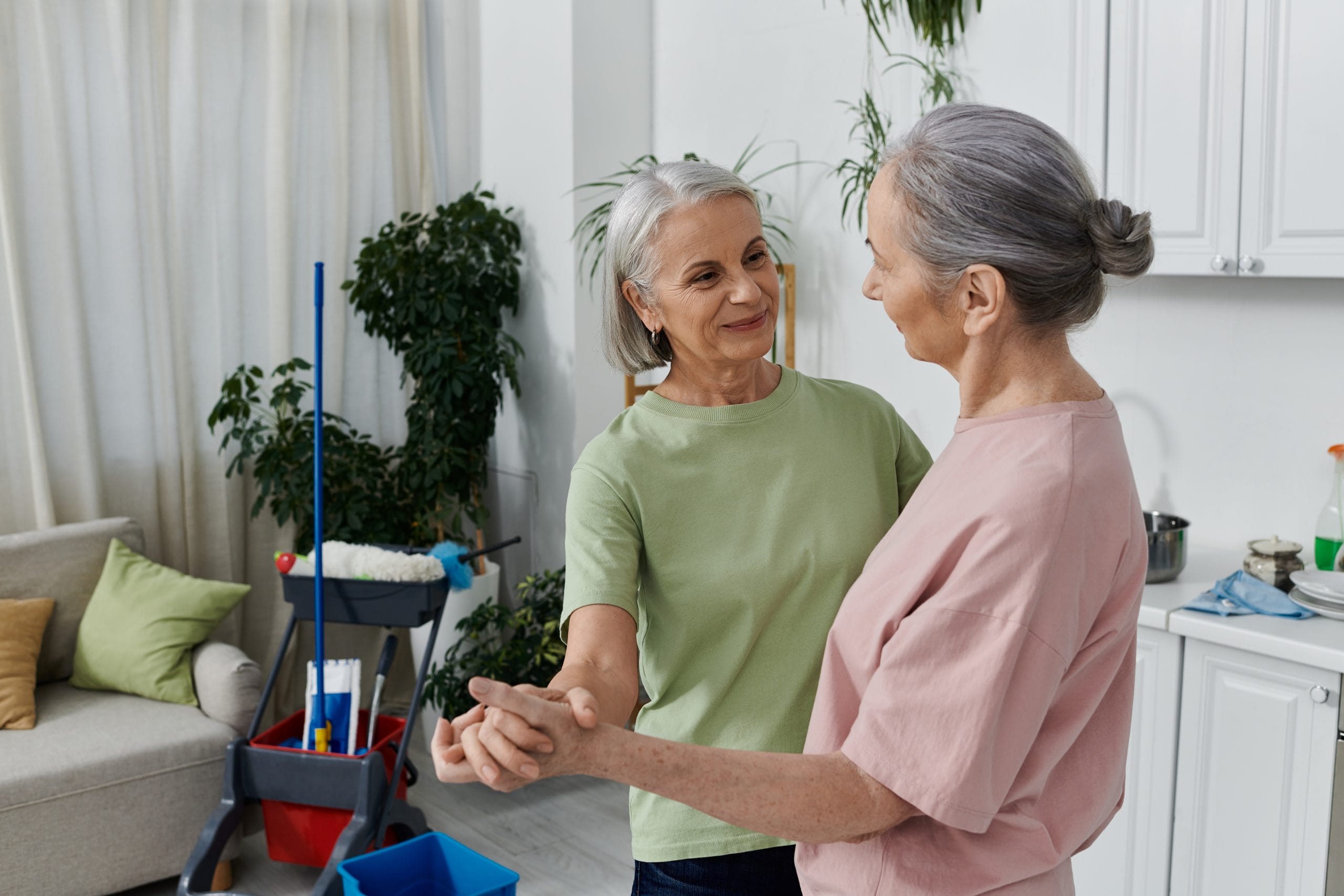AdobeStock_870556154 An older lesbian couple cleans their modern apartment together, laughing and enjoying each others company.
